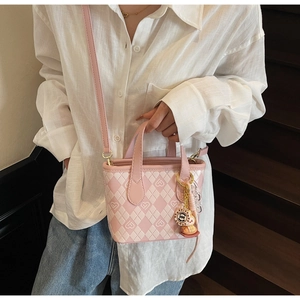 Borsa a secchiello trapuntata rosa con motivi a cuore e ciondolo indossata da una modella