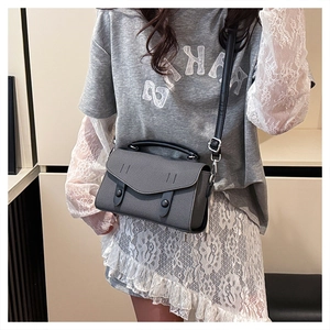 Detailed view of the gray trapezoid crossbody bag with black straps on a model