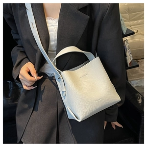 Detail of white lychee pattern bucket bag featuring a wide handle and adjustable shoulder strap