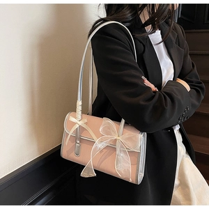 Detailed side view of a pink lace bow shoulder bag with silver trim on a fashion model