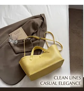 Detail of yellow pebbled leather tote bag with top handle and decorative buckle