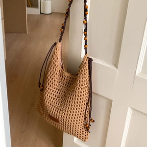 Detail of bohemian hollow-out crochet beach bag with wooden bead shoulder strap
