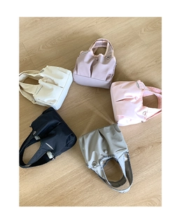 Detail of five colorful pleated nylon tote bags arranged on a light wooden floor background