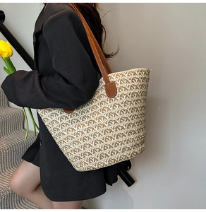 Dettaglio di una borsa tote intrecciata con motivo a onde bicolore e manici in pelle