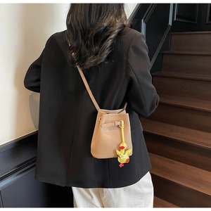 Litchi texture khaki bucket bag with cute yellow duck pendant shown on a model