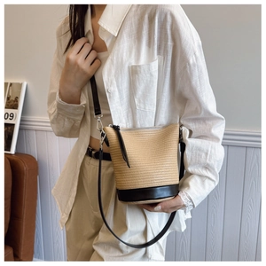 Detailed straw bucket bag with black leather base and stitching in a casual summer style