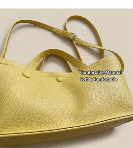 Detail of yellow pebbled leather bucket bag featuring a magnetic snap and adjustable strap