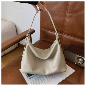 Close-up of cream hobo bag with adjustable strap and silver zipper detail