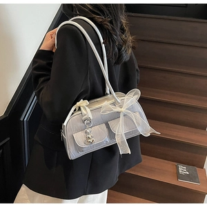 Silver saddle bag with lace bow and heart charms shown on model on wood stairs