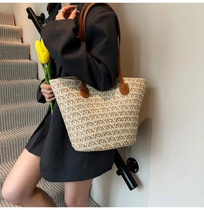 Dettaglio della borsa tote in paglia intrecciata beige con spalline in pelle marrone
