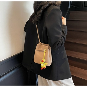 Close-up of beige lychee grain bucket bag with a cute yellow duck pendant detail