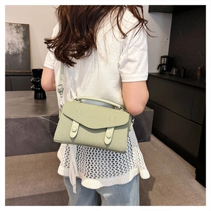 Detail view of light green crossbody bag with fine texture and silver metal hardware accents