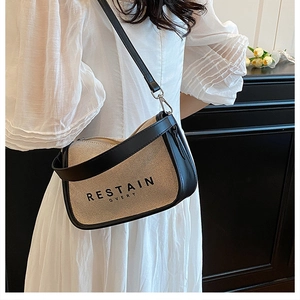 Detail of beige canvas crossbody bag with black leather trim and artistic typography