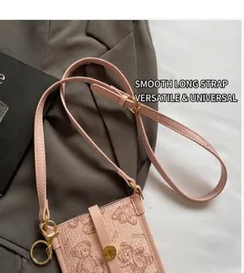Detail view of pink leather phone bag featuring a bear print and gold metallic hardware