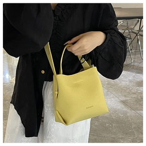 Detail view of yellow lychee pattern leather bucket bag with brand logo and strap