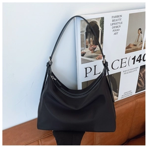 Fashionable black nylon hobo bag on a sofa with magazines for casual commute look