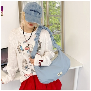 Nahaufnahme der hellblauen Falten-Tasche mit weißem Logo-Label und Nylon-Struktur