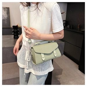 Detail of woven texture and double buckle flap on light green crossbody bag
