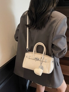Borsa a mano beige in pelle martellata con dettagli argento portata a tracolla