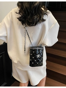 Sac seau matelassé noir élégant avec clous argentés et bandoulière chaîne sur modèle