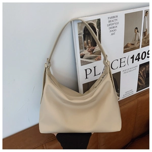 Detail of a cream beige leather hobo bag with adjustable strap and metal hardware