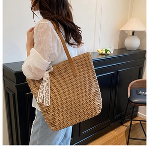 Close-up of woven straw tote bag with white lace ribbon and brown leather straps
