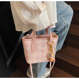 Dettaglio borsa a secchiello rosa trapuntata con logo a cuore e ciondolo su modella