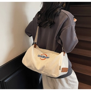 Détail du sac à bandoulière en toile avec broderie et rivets en cuir marron
