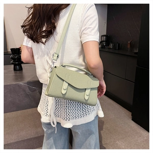 Detail of green textured crossbody bag featuring woven pattern and adjustable shoulder strap