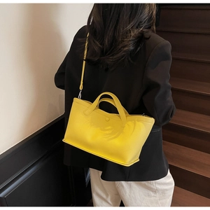 Detail of bright yellow lychee leather bucket bag showing texture and shoulder strap