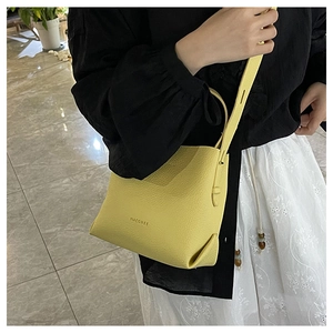 Close-up of lemon yellow litchi pattern bucket bag with adjustable strap on model