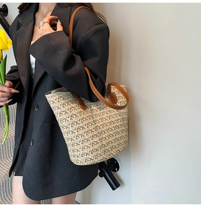 Dettaglio della borsa tote in paglia intrecciata con manici in pelle marrone