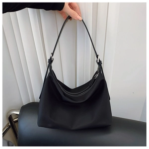 Detail view of the black tote bag featuring nylon fabric and silver metal hardware
