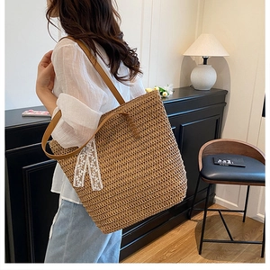 Detail of straw tote bag with brown leather straps and elegant white lace bow detail