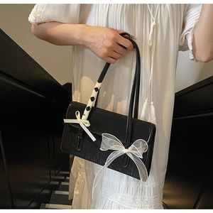 Close-up of elegant black bag featuring a white organza bow and ribbon-wrapped handle