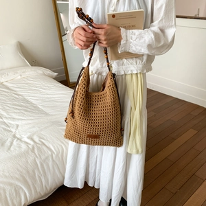 Detail of hollow woven texture and vintage wooden bead strap on the brown tote bag