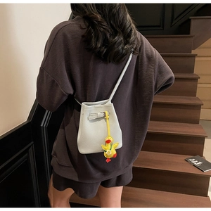 Detail of light blue bucket bag with lychee texture and cute yellow duck charm