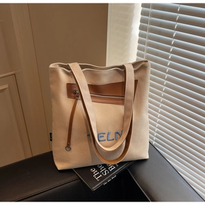 Détail du sac cabas en toile beige avec broderie CELN et garniture en cuir marron