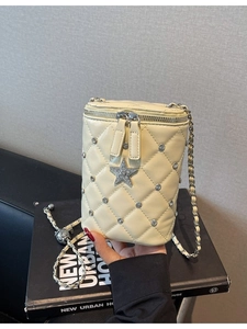 Sac seau matelassé beige avec pendentif étoile et bandoulière chaîne porté à la main