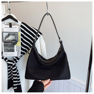 Close-up of lightweight black nylon hobo bag with leather strap on a clothing rack