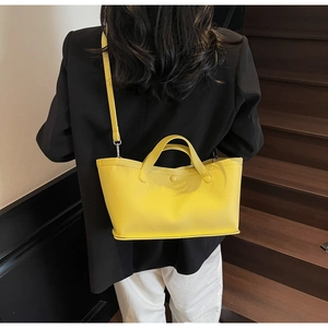 Macro shot of bright yellow lychee texture leather tote bag worn by a model