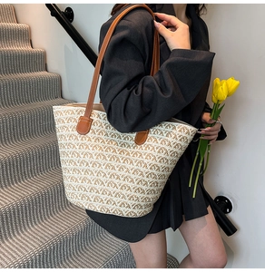 Dettaglio della borsa tote in paglia intrecciata con manici in pelle marrone e onde beige