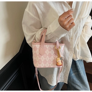 Dettaglio borsa a secchiello rosa a rombi con ciondolo a coniglio e tracolla in pelle