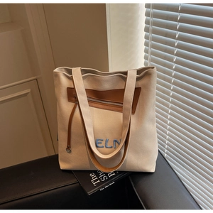 Détail d'un sac en toile beige avec garniture en cuir brun et broderie ELN bleue