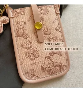 Close-up of light pink crossbody phone bag with teddy bear print and lychee texture