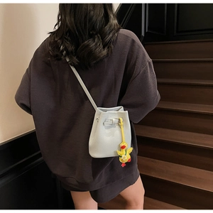 Detail of light blue lychee pattern bucket bag with cute yellow duck plush pendant