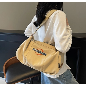 Détail du sac fourre-tout en toile beige avec broderie orange et bandoulière large