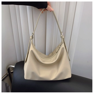 Detail of beige faux leather tote showing adjustable strap and silver metal buckle