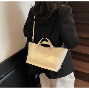 Close-up of cream textured leather tote bag showing fine stitching and silver hardware