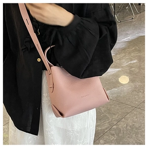 Detailed view of pink lychee leather bucket bag with brand logo and crossbody strap